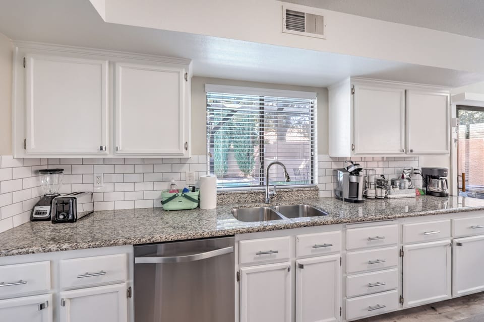 Bright kitchen with granite, subway tile, and a stocked coffee bar