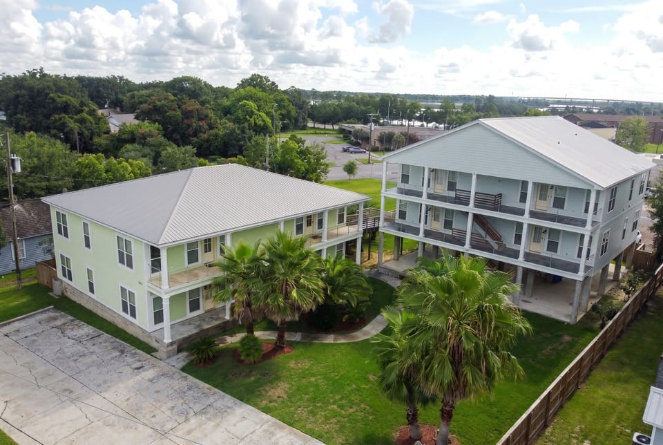 Coastal duplex retreat with balconies, palm trees, and spacious shared lawn