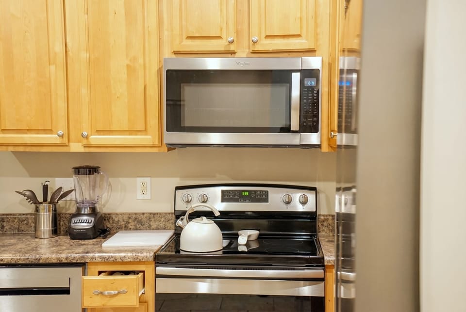 Well-equipped kitchen with stainless appliances and warm wood cabinets