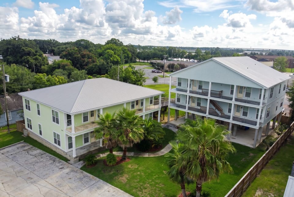 Spacious coastal retreat with balconies, palm trees, and shared courtyard
