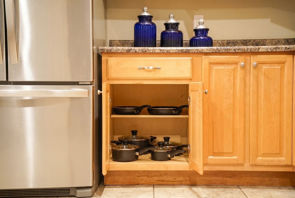 Well-stocked kitchen with cookware, wood cabinets, and stainless fridge