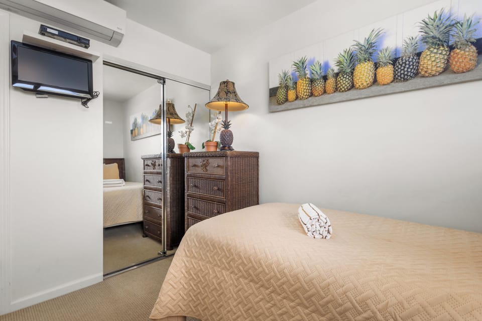 Unwind in your cozy bedroom with tropical-inspired decor, wall-mounted TV for entertainment, and quiet comfort. Fresh towels await your arrival.