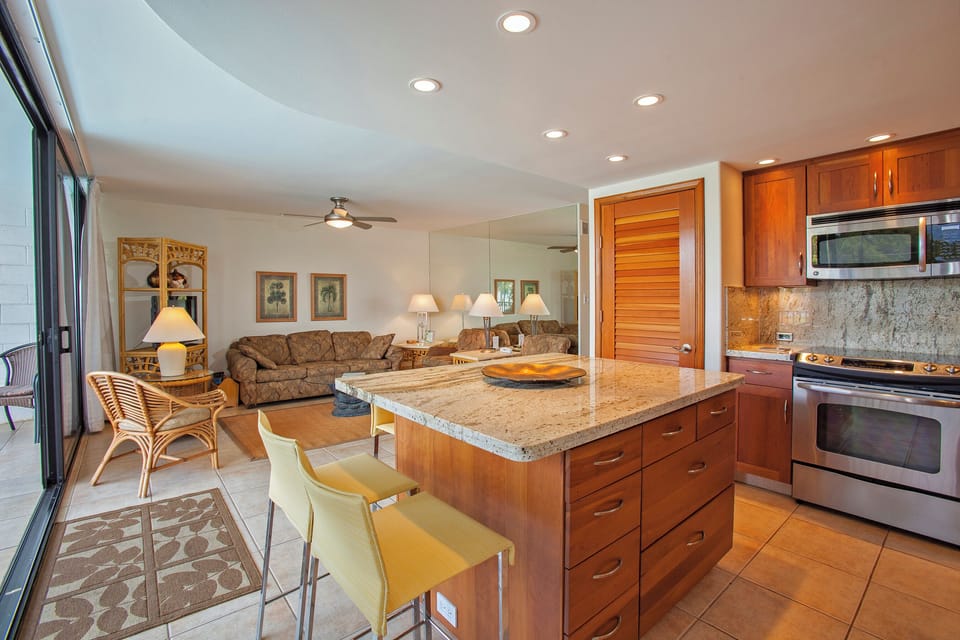 Open living with a granite-topped island, rich wood cabinetry, and modern appliances flows seamlessly into the cozy lounge—perfect for gathering after a day exploring paradise.