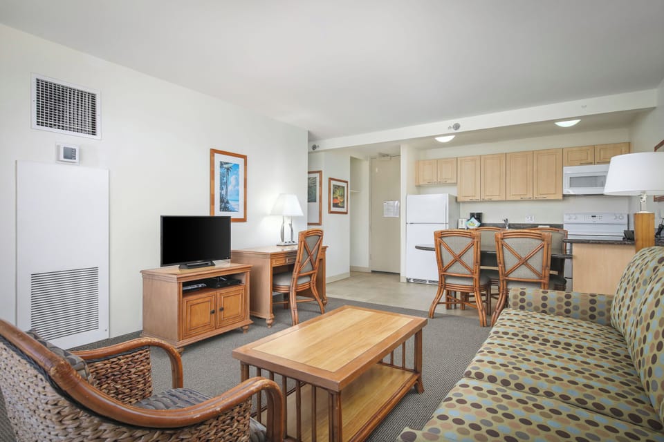 Relax in your open-concept living space featuring a cozy seating area, flat-screen TV, and fully equipped kitchen with modern appliances—perfect for making yourself at home.