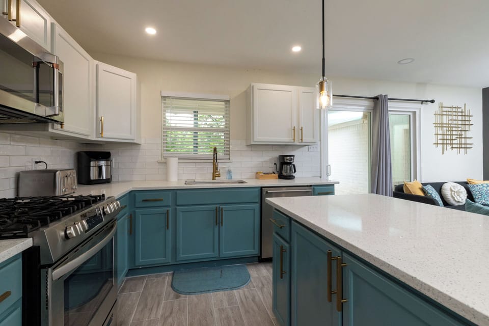 Modern gas range and microwave with subway tile and gold hardware