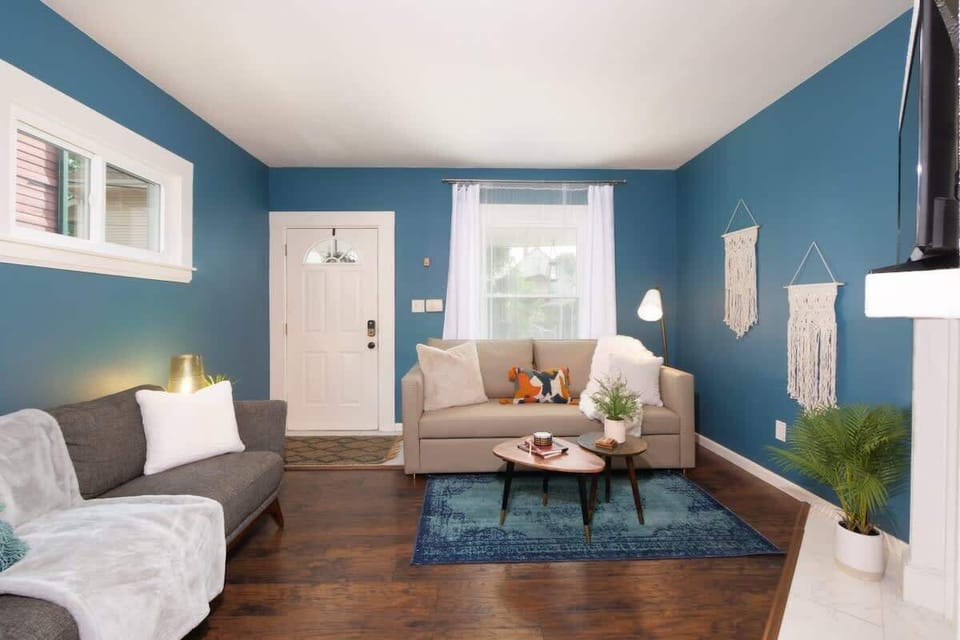 Cheerful living room w/ cozy seating, bright windows & a wall-mounted TV for relaxed movie nights