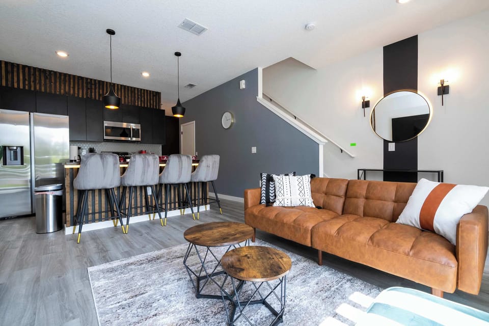 Modern, open-concept lounge flows into a chic kitchen-relax on the leather sofa or gather at the island for 4 beneath warm pendants and wood-slat accents.