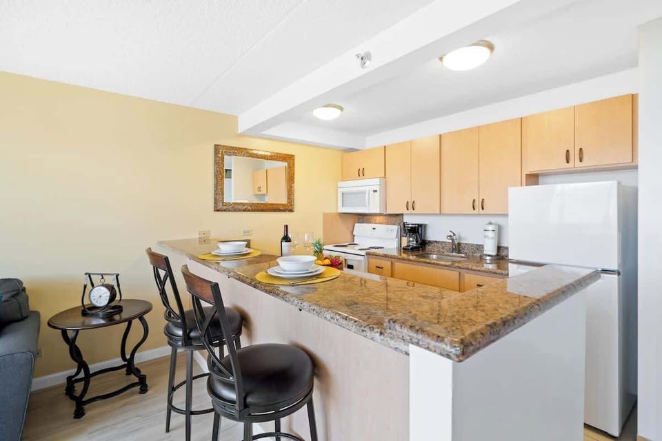 Prepare your favorite meals in this fully-equipped kitchen featuring granite countertops, ample cabinet space, and a breakfast bar with seating for two.