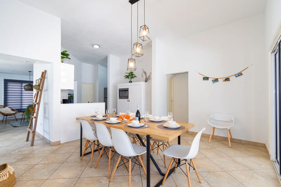 Lush Living and Dining Area of the 3BR house in Noord Aruba - Open-concept living area seamlessly connected to a stylish dining space - 8 Persons Dining - Cohesive design aesthetic carried through from furniture to window treatments