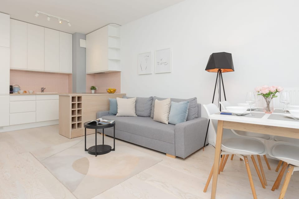 Open-plan living space featuring a comfortable sofa, kitchen area, and natural lighting.

