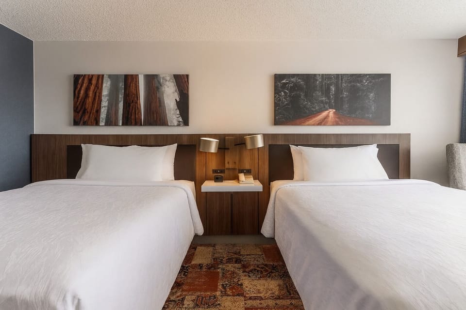Unwind in crisp double-queen comfort with warm bedside lighting.