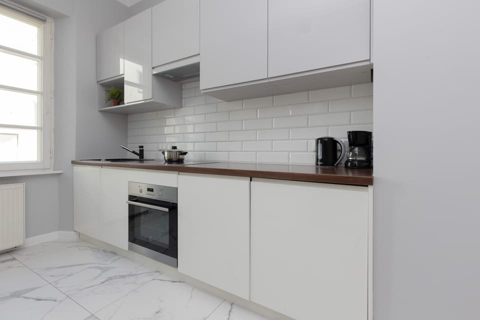 A modern kitchen with sleek white cabinetry, subway tile backsplash, and built-in appliances, offering everything needed for meal preparation.