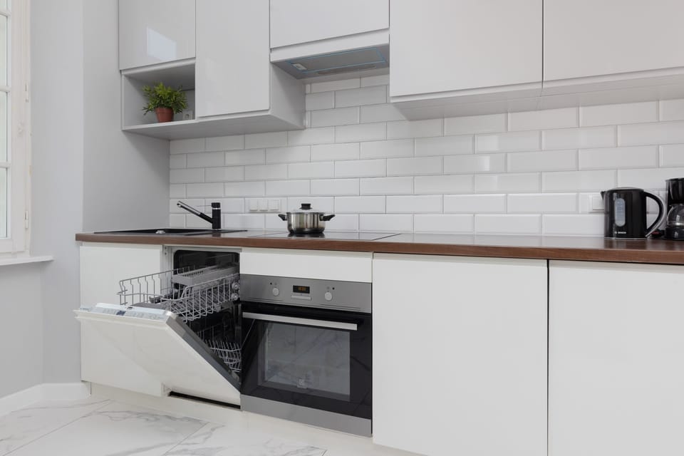 A modern kitchen with sleek white cabinetry, subway tile backsplash, and built-in appliances, offering everything needed for meal preparation.