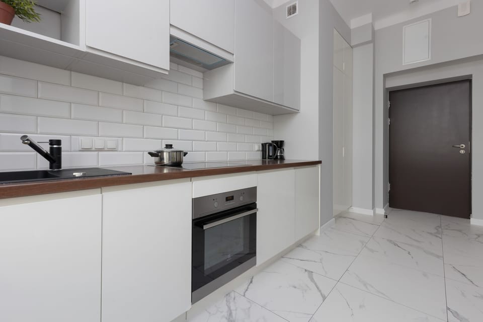 A modern kitchen with sleek white cabinetry, subway tile backsplash, and built-in appliances, offering everything needed for meal preparation.