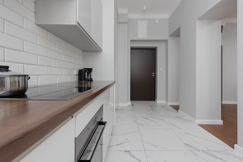 A modern kitchen with sleek white cabinetry, subway tile backsplash, and built-in appliances, offering everything needed for meal preparation.