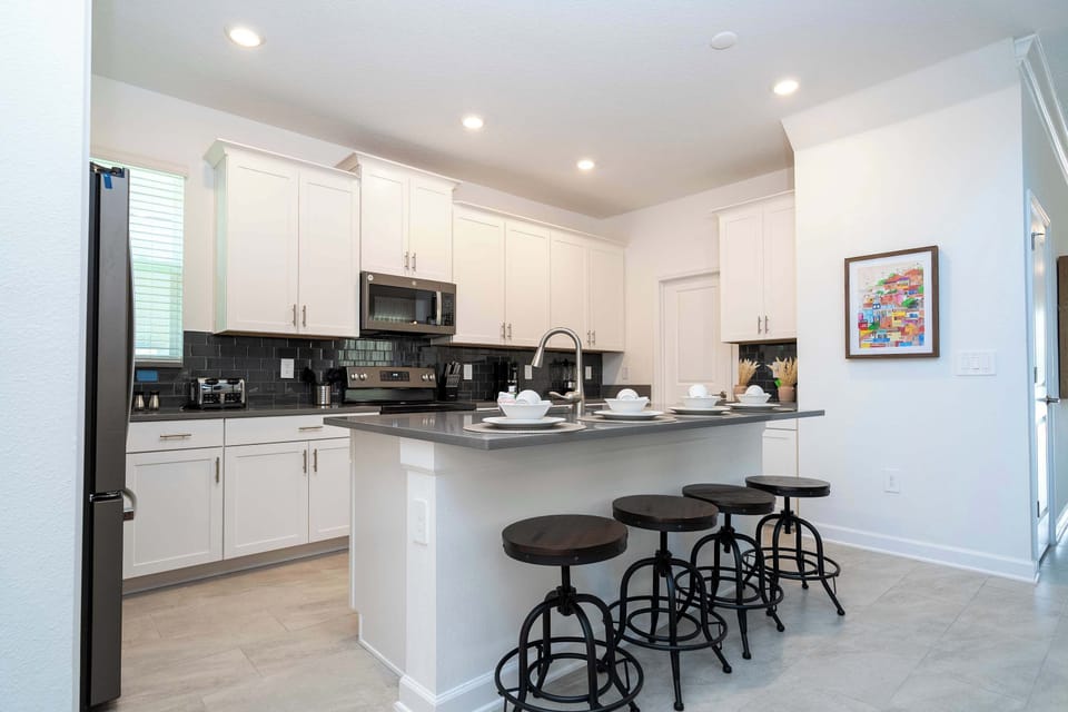 Our modern kitchen is a chef's dream! With sleek white cabinetry, a large island, and seating for four, it's the heart of the home for family breakfasts.
