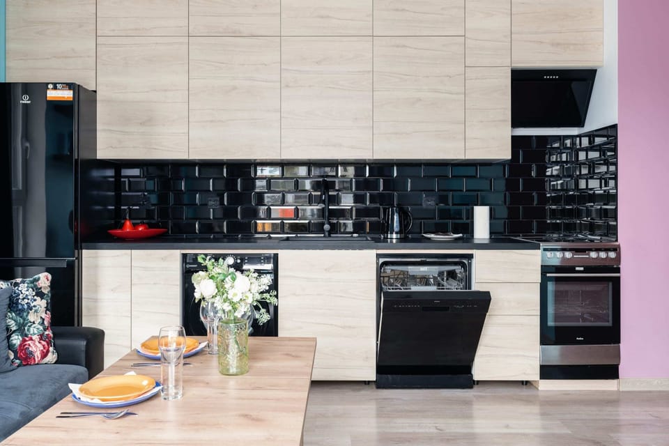 Contemporary kitchen with wood and black finishes, a stylish backsplash, and modern appliances.

