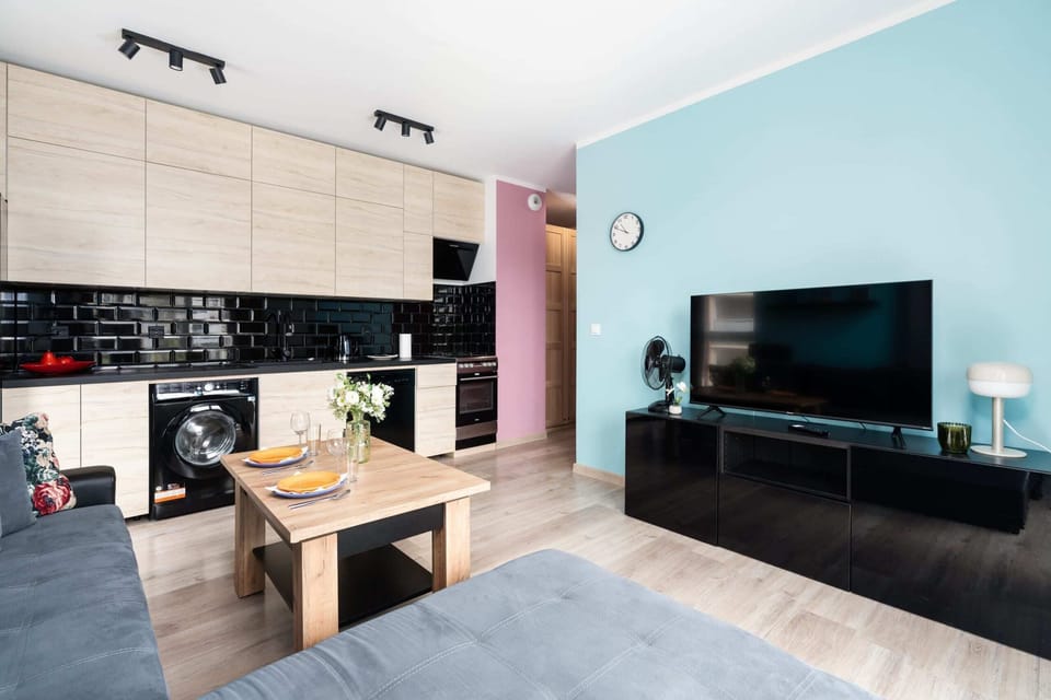Open living space with a wall-mounted TV and a sleek, modern kitchen.

