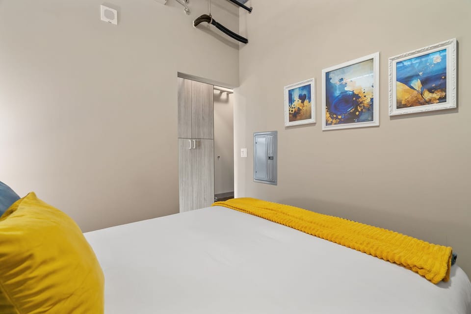 Sink into your comfortable bed surrounded by cheerful yellow accents and ocean-themed art that creates a serene, coastal vibe.