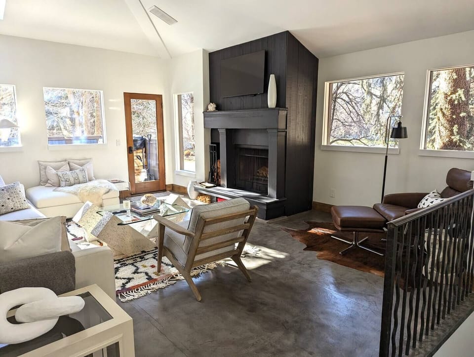 Bright light living area with wood burning fireplace and deck with hot tub.