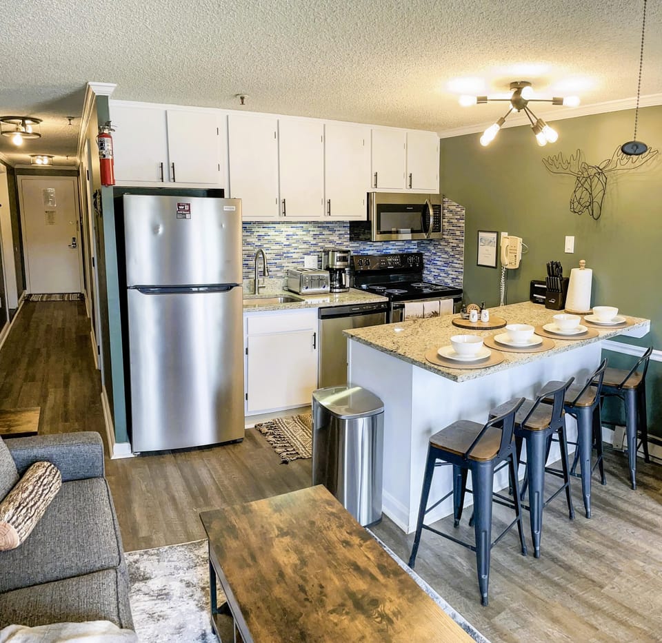 The modern kitchen features granite countertops, stainless steel appliances, and a wine fridge.
