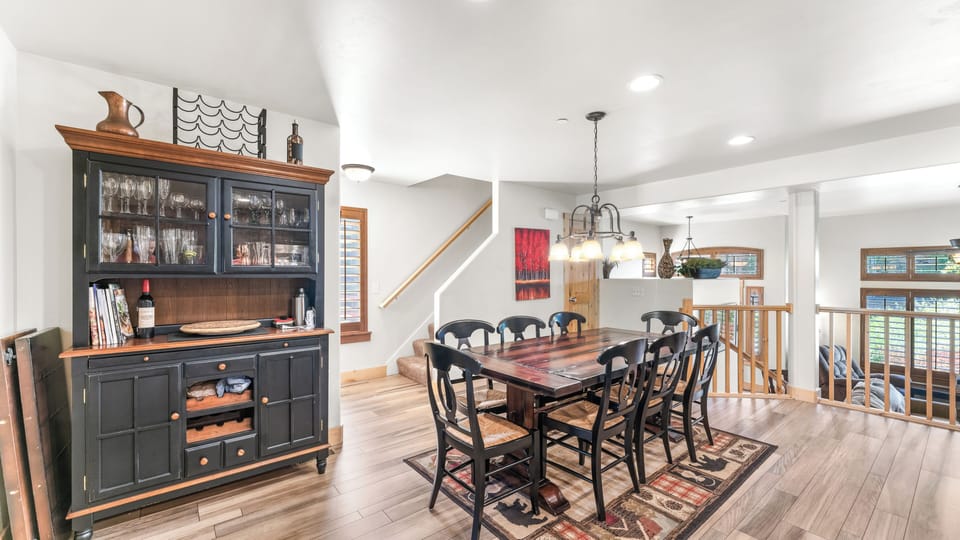 - Rustic dining area with black chairs and wood table centerpiece  
- Bright windows and warm lighting create a welcoming dining space  
- Enjoy family meals and easy flow into kitchen and living areas