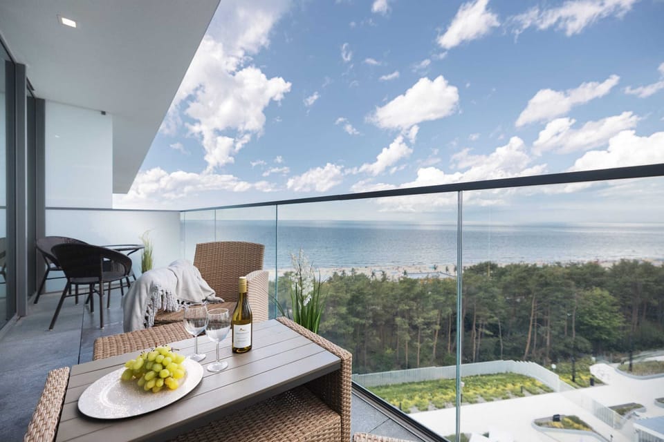 Spacious balcony overlooking lush greenery, with a cozy dining setup perfect for morning coffee.

