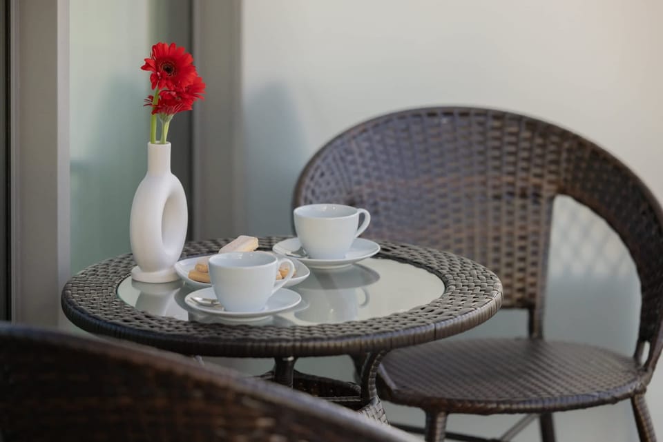 Intimate dining setup with wicker furniture and a vase of flowers, perfect for enjoying a peaceful moment.

