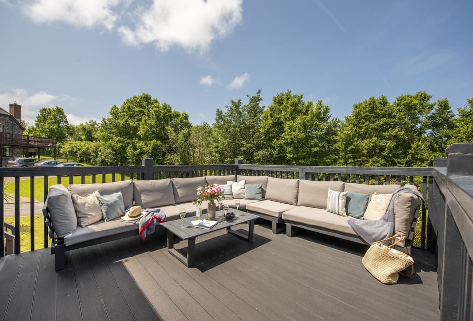 The Hawthorns, Roserrow: Large decked terrace overlooking the spacious garden with outdoor furniture; access is via the first floor.