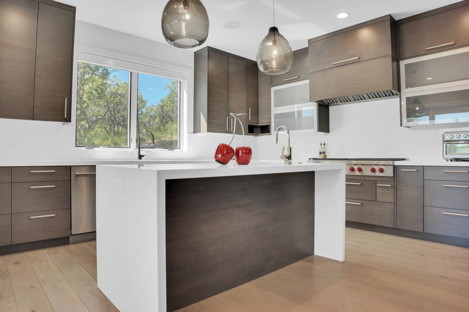 The vacation rental kitchen with a large window over the sink looking out to the oak grove.