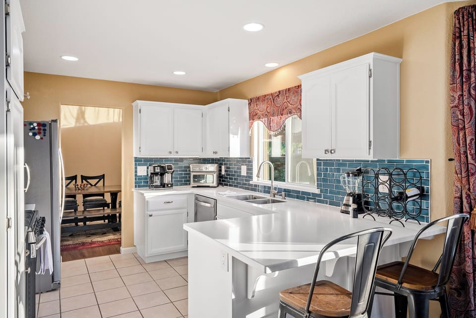 A sleek and modern kitchen featuring a convenient breakfast bar with industrial-style metal stools, an ideal spot for casual dining or morning coffee.