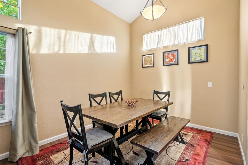 A cozy dining area featuring a sturdy wooden table with matching bench and chair seating, set against warm-toned walls.