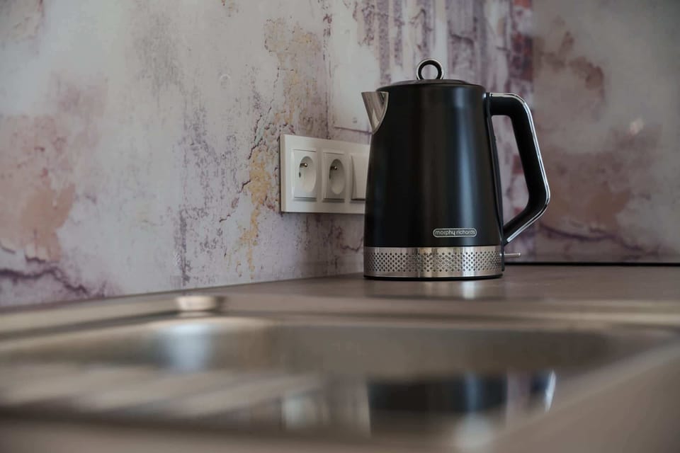Close-up of a coffee and tea setup with a kettle on a sleek countertop.

