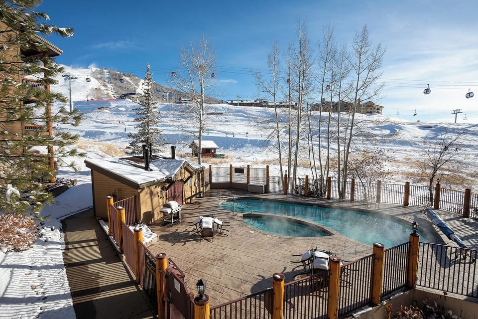 Pool deck with stunning ski slope views and gondola system visible across the snowy mountain landscape.