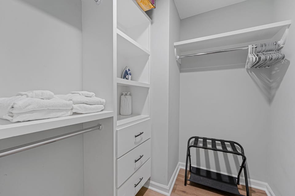 Spacious walk-in closet with built-in shelving, drawers, hanging space, and luggage rack.
