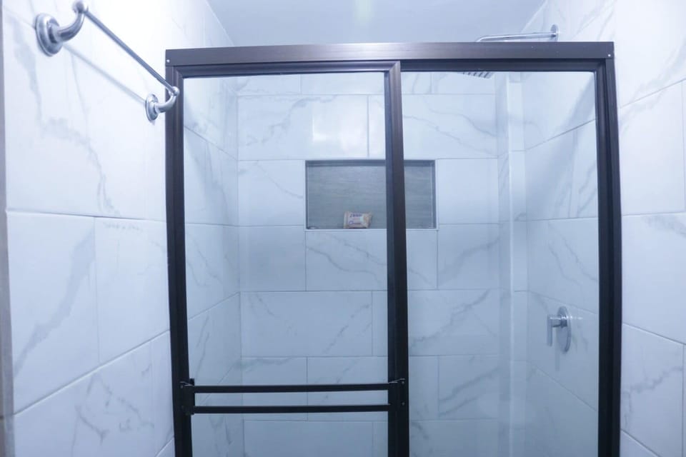Ducha con agua caliente, baño espacioso cabinado en vidrio.