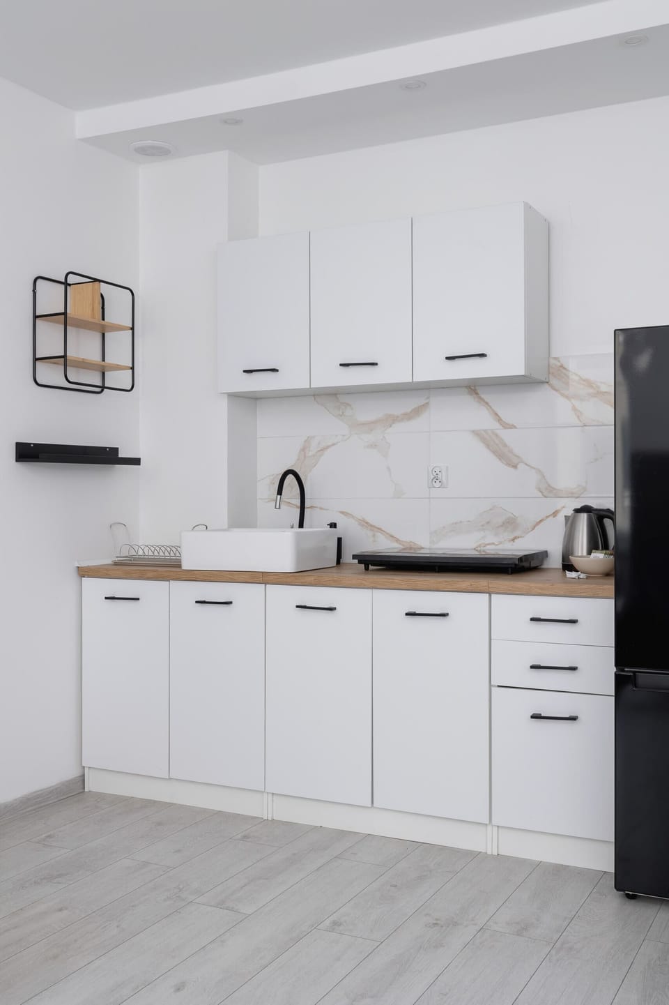 Modern kitchen with white cabinets, marble countertops, and a compact yet functional design.

