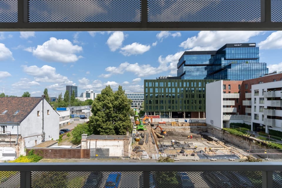 Scenic view from the building overlooking a vibrant neighborhood and urban greenery.

