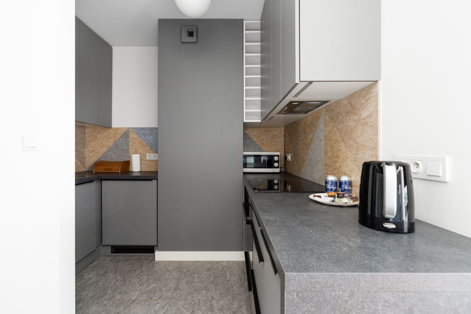Fully equipped kitchen with modern appliances and natural stone backsplash.

