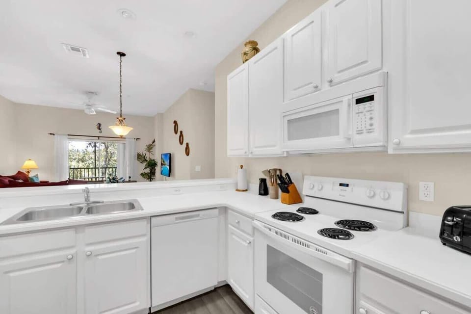 Bright kitchen with white cabinetry and modern appliances overlooking the living area.