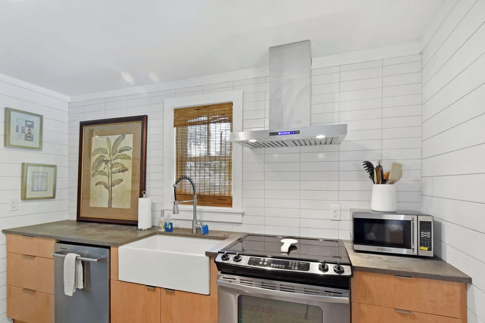 Kitchen with Farmhouse Sink - Bright kitchen with farmhouse sink, electric range, microwave, dishwasher, and tile backsplash.