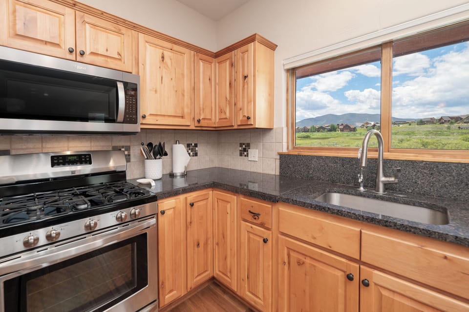 Your fully equipped kitchen features warm wood cabinetry and granite counters, with mountain views inspiring your culinary adventures.