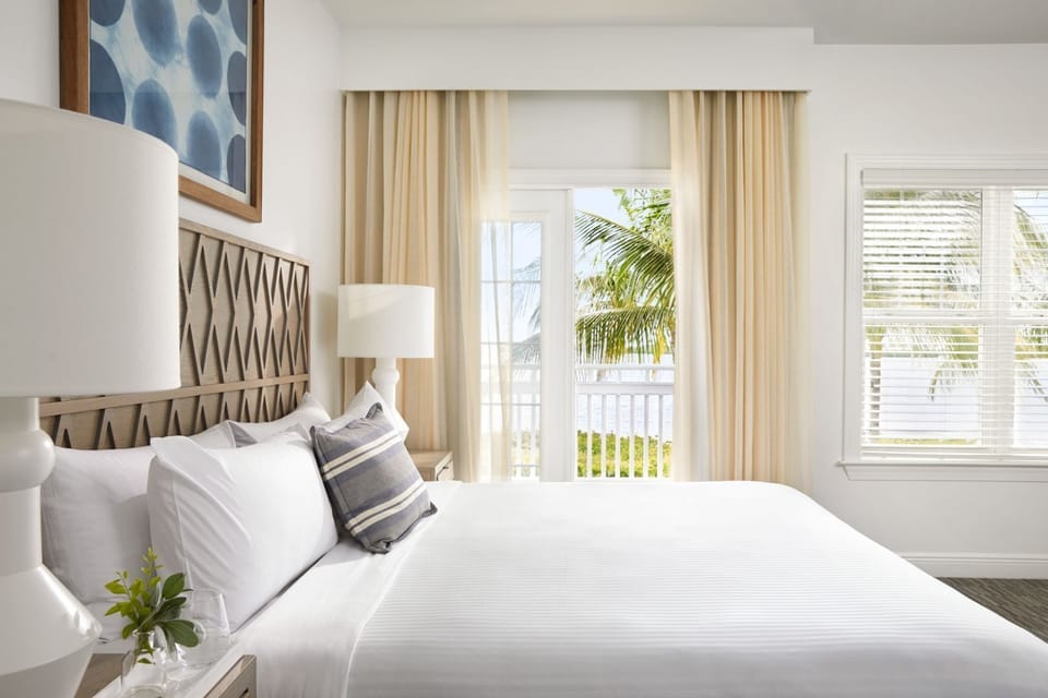 Sink into crisp linens beside soft drapes and airy windows.