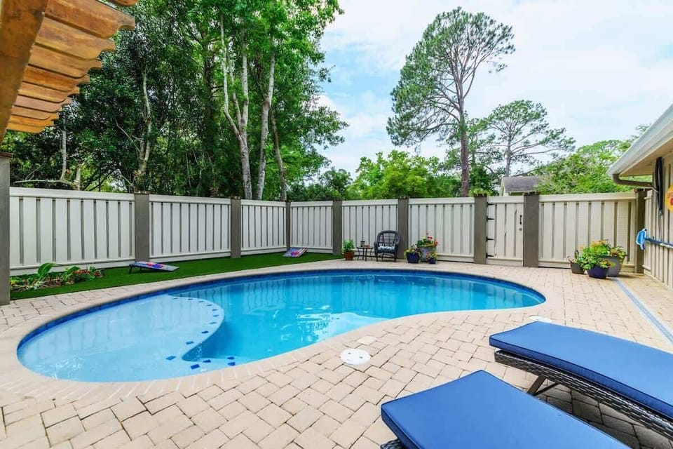A pristine, kidney-shaped pool surrounded by a spacious paver patio.