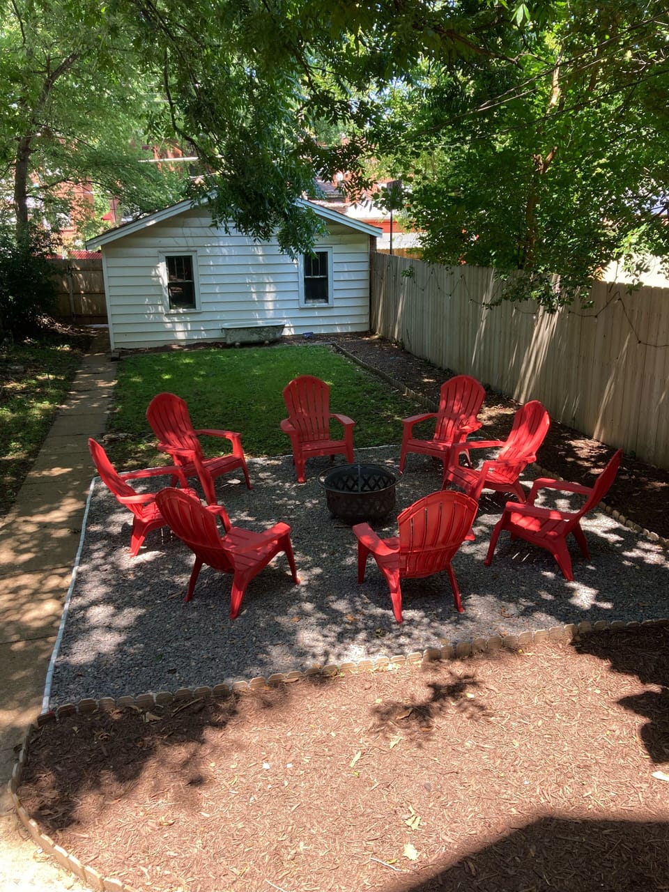 Backyard with fire pit and string lights. Enjoy some s'mores!