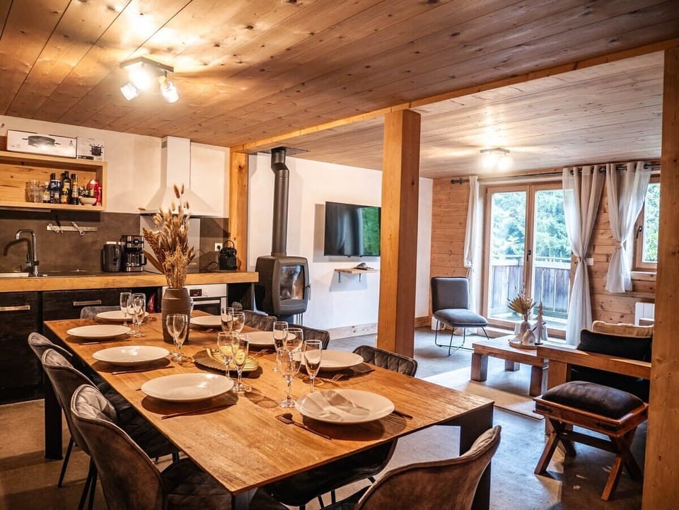 Pièce de vie principale, avec grande table à manger, cuisine équipée, canapé, table basse et poële à bois