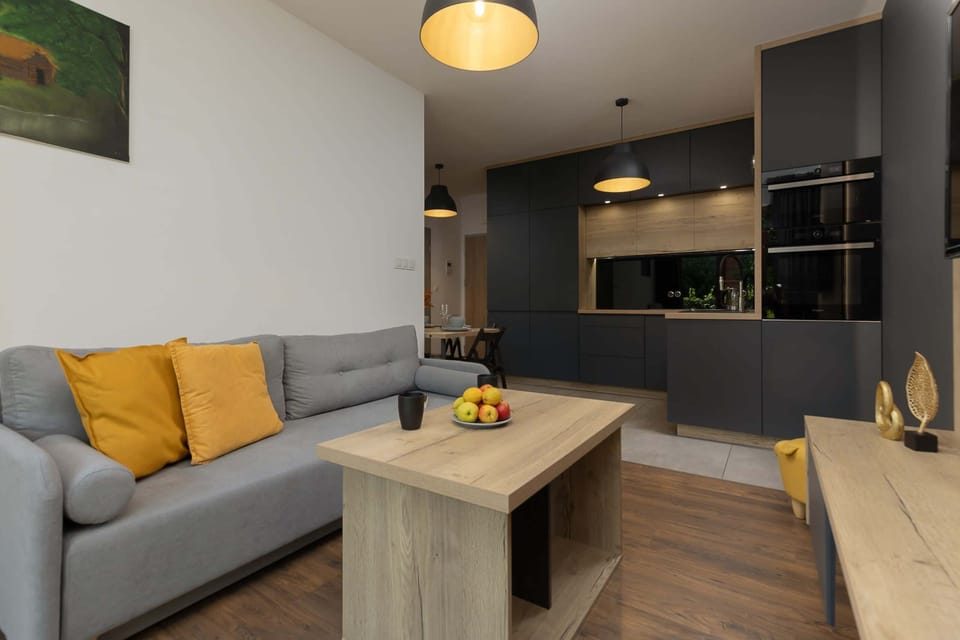 Stylish living room with a grey sofa, warm wooden furniture, and natural lighting.

