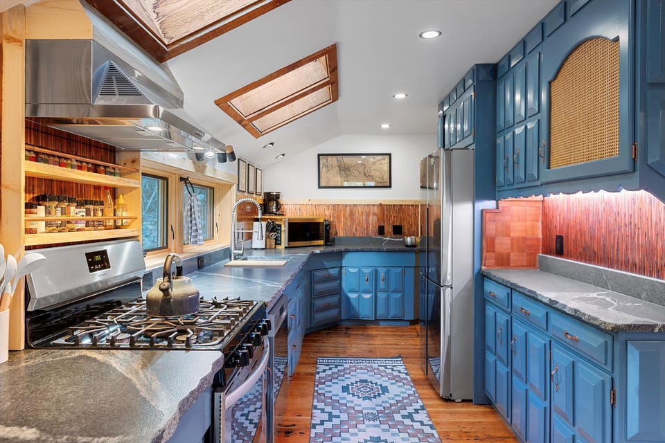 The cooks kitchen features live-edge granite countertops, copper backsplash, & stainless appliances.