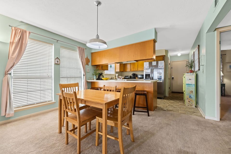 Dining area with natural light and a view into the kitchen featuring wooden cabinetry.