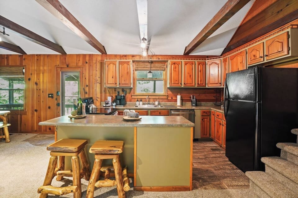 Create delicious meals in the fully stocked kitchen featuring warm wood cabinetry, full-size refrigerator, Keurig Duo coffee maker, and a spacious island with rustic barstools, perfect for cooking, dining, and gathering with family and friends.